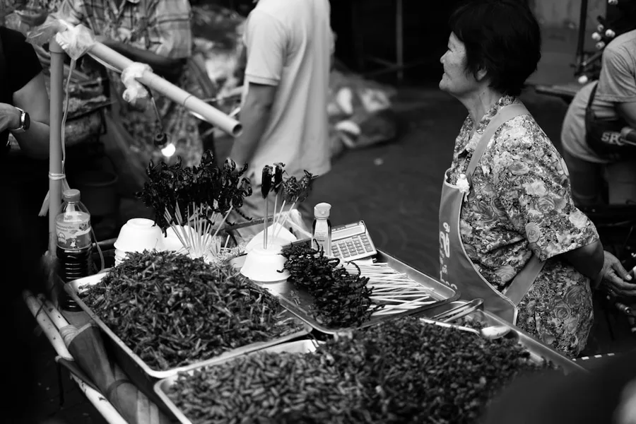young couple paying with crypto app at 7-Eleven in Bangkok street food market
